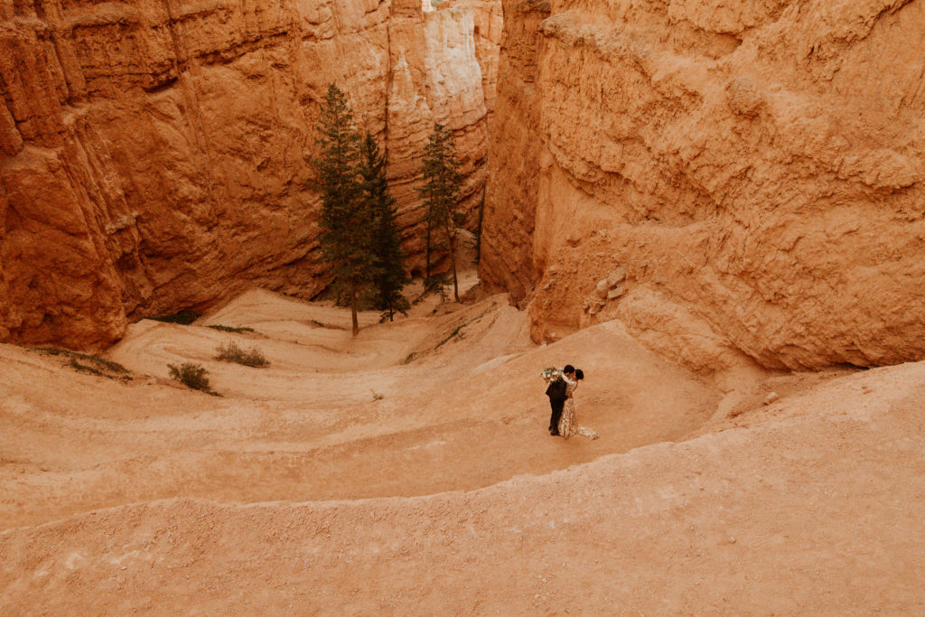 Bride & Groom Hiking in Bryce Canyon National Park on the switchbacks of the Navajo Loop hiking trail as part of their elopement where they exchanged their vows
